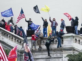 FILE - Rioters wave flags on the West Front of the U.S. Capitol in Washington on Jan. 6, 2021. Federal prosecutors say a network of supporters has helped fugitives from Florida avoid capture to face charges stemming from the riot. Prosecutors argued Thursday, March 14, 2024, that a Jan. 6 defendant, Thomas Osborne, is a flight risk because he is close to the family of a brother and sister from Lakeland, Fla. who remained on the run for months after they were charged with storming the Capitol.