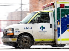 An ambulance makes its way through the falling snow in downtown Edmonton, Friday Jan. 27, 2023.