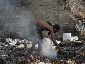 A man searches through burning trash ,in Port-au-Prince, Haiti, on April 13, 2024.
