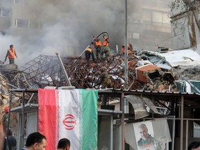 Emergency and security personnel extinguish a fire at the site of strikes which hit a building annexed to the Iranian embassy in Syria's capital Damascus, on April 1, 2024.