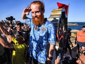 British runner Russ Cook gestures as he poses for a picture with the memorial sign marking the northern-most point of Africa upon arrival at Cape Angela, northeast of Tunis, on April 7, 2024.