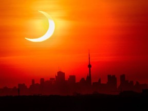 An annular solar eclipse rises over the skyline of Toronto on Thursday, June 10, 2021.