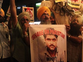 FILE - Indian Sikhs shout slogans against Pakistan as they display photographs of Sarabjit Singh, center, a convicted Indian spy who was on Pakistan's death row, died from a head injury after two inmates attacked him with a brick in a Lahore jail, during a protest in Kolkata, India, Thursday, May 2, 2013. A Pakistani police official says an investigation has begun after a man suspected in a fatal attack on an imprisoned Indian national more than a decade ago was shot dead at his home in the eastern city of Lahore.