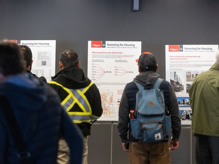  Members of the public look over poster boards outlining the City of Calgary’s proposed blanket rezoning plan at city hall on the first day of a public hearing into the plan on Monday, April 22, 2024.