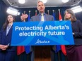 Affordability and Utilities Minister Nathan Neudorf speaks as Parliamentary Secretary for Affordability and Utilities Chantelle De Jonge, left, and Premier Danielle Smith listen as he introduces legislation to lower fees for utility bills and help to keep people more informed about their options on Monday, April 22, 2024, in Edmonton.