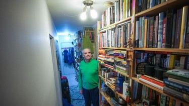 John William, who is losing his sight, poses for a photograph with his collection of books that he has decided to sell, in Vancouver, on Wednesday, April 24, 2024.