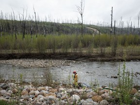 A firefighters monitors a pump in a river bed used for wildfire sprinklers in the evacuated neighbourhood of Grayling Terrace in Fort McMurray, Alta., Thursday, May 16, 2024.