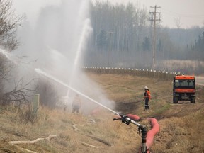 Workers inspect sprinklers blasting water at trees outside Gregoire Lake Estates as a precautionary measure against wildfires on May 15, 2024.