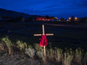 A child’s dress is seen on a cross outside the former residential school in Kamloops, B.C., on June 13, 2021.