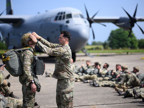 U.S. and Belgian paratroopers check their equipment prior to their jump from a Lockheed C-130 Hercules aircraft in Cherbourg, France, ahead of D-Day 80th anniversary events, on June 5, 2024.