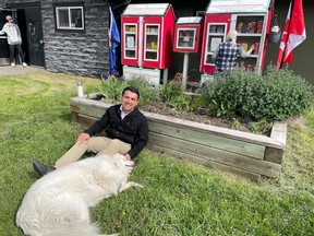 Syed Hassan, founder and president of Love With Humanity Association, sits with a dog outside the organization’s new outdoor pet food bank at the Albert Park/Raddison Heights Community Association.