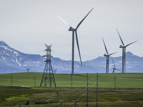 Decarbonizing Canada's electricity grid could lead to a significant uptick in merger and acquisition activity in the renewable energy sector, a new report says. Power transmission lines and wind turbines as seen with the Rocky Mountains in the background near Pincher Creek, Alta., Thursday, June 6, 2024.