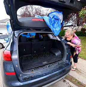 Ani Banks looks over the hail damage to her vehicle in Coventry Hills on Aug. 6.