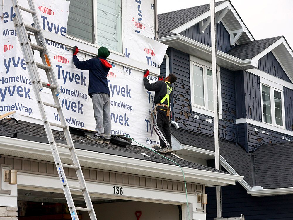 Workers replace siding on a row of hail-damaged homes in the northeast community of Redstone on Wednesday. 