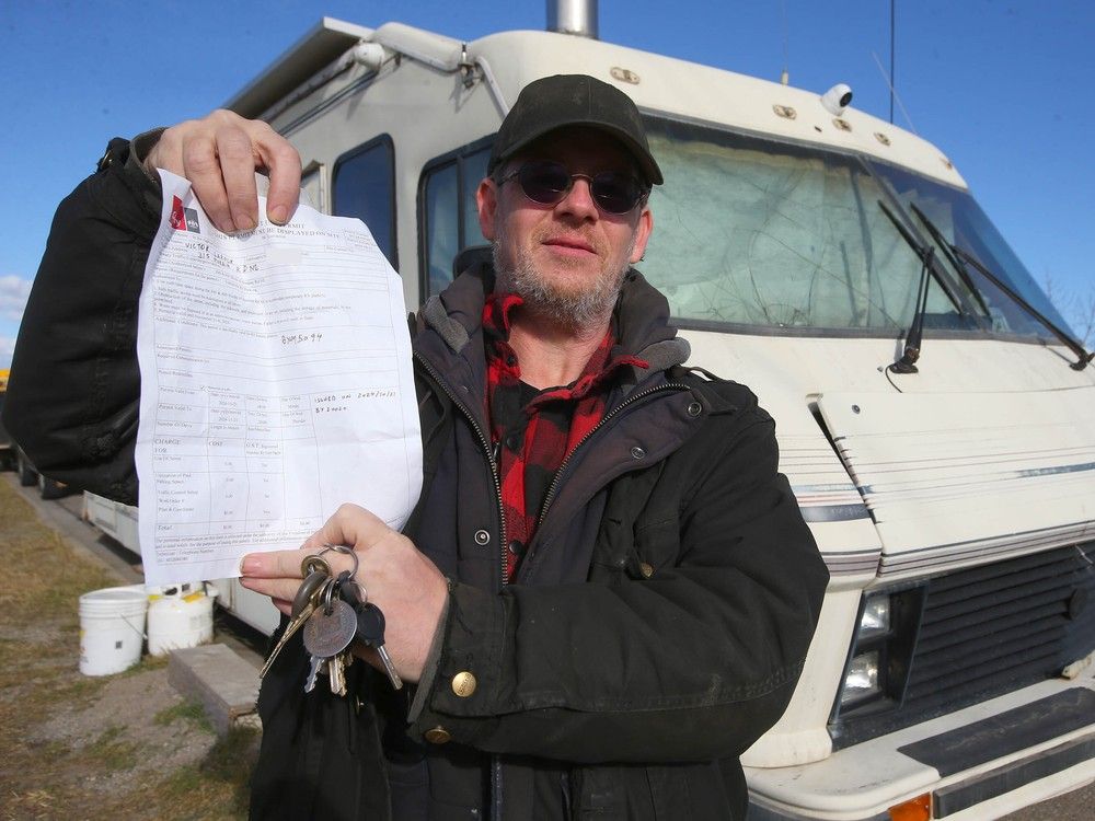 Victor LaRock poses with a 30 day City of Calgary parking permit as he discusses his living situation on Moraine Rd NE in Calgary on Thursday, October 24, 2024. He has lived in his RV for over ten years and is part of a group asking for a solution where to park their RVs where they live full time. NOTE: IMAGE ALTERED TO REMOVE SUBJECT'S PERSONAL PHONE NUMBER. 