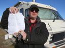 Victor LaRock poses with a 30 day City of Calgary parking permit as he discusses his living situation on Moraine Rd NE in Calgary on Thursday, October 24, 2024. He has lived in his RV for over ten years and is part of a group asking for a solution where to park their RVs where they live full time. NOTE: IMAGE ALTERED TO REMOVE SUBJECT'S PERSONAL PHONE NUMBER.