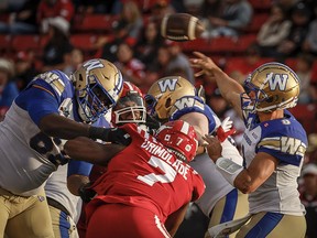 Winnipeg Blue Bombers quarterback Zach Collaros, right, throws the football as Calgary Stampeders' Folarin Orimolade closes in during second half CFL football action