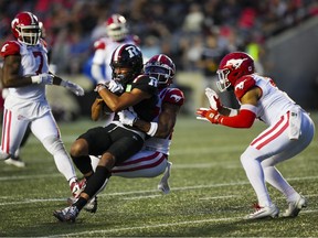 Ottawa Redblacks wide receiver Keelan White (81) gets tackled by Calgary Stampeders defensive back Godfrey Onyeka (centre) during first half CFL football action in Ottawa on Thursday