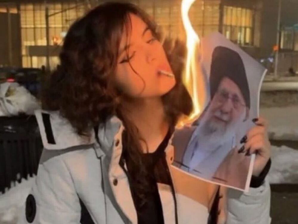 An Iranian refugee in Canada who is known as Morticia Addams (not her real name) lights a cigarette with an image of Iran's leader, Ali Khamenei, in a picture taken in Richmond Hill.