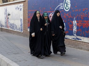 Women walk past a mural painted on the outer walls of the former U.S. embassy in Tehran, Feb. 1, 2026.