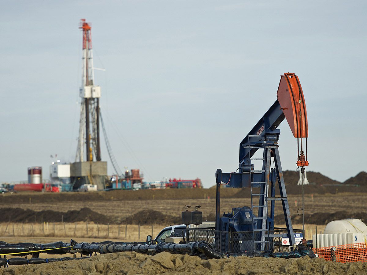 A pumpjack and drilling rig in Alberta