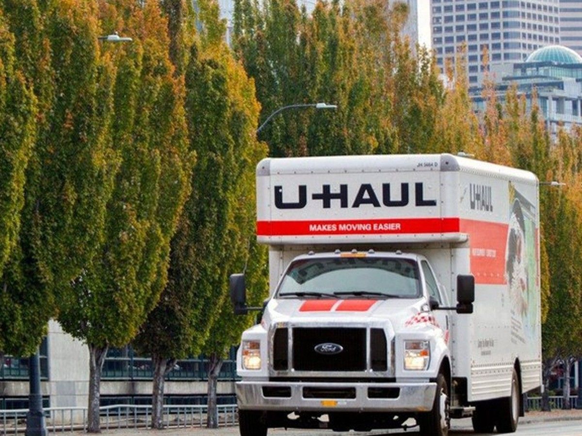 A U-HAUL moving van driving across a New Brunswick road, with wildlife and city in the background.