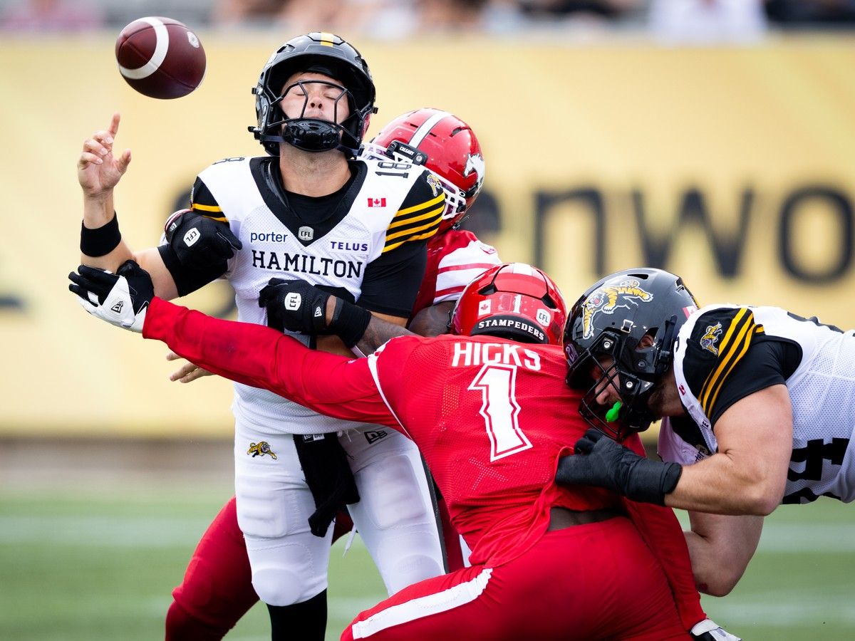 Hamilton Tiger Cats quarterback Harrison Frost(18) is hit by Calgary Stampeders linebacker Marquel Lee(8) and fumbles the ball during first quarter CFL game