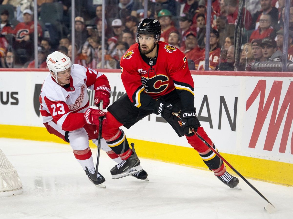 Kevin Bahl #7 of the Calgary Flames skates with the puck as he's chased by Lucas Raymond #23 of the Detroit Red Wings during the first period at the Scotiabank Saddledome