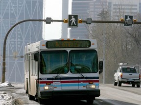 A Calgary Transit bus heads northbound on Centre ST near 8 Ave N with the downtown skyline in the background.