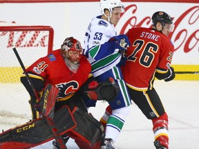 Canucks Bo Horvat (C) is pinned between Flames goalie Mike Smith (L) and defencman Michael Stone during NHL action between the Calgary Flames and Vancouver Canucks in Calgary on Tuesday, November 7, 2017. Jim Wells/Postmedia