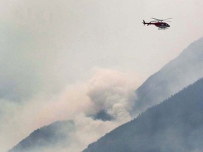 A helicopter flies above the plumes of smoke near Waterton Lake on Wednesday, September 13, 2017 south of Pincher Creek. Jim Wells/Postmedia