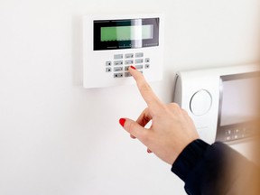 Young woman entering security code on home security alarm system keypad