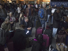 Passengers wait in a dark terminal at Hartsfield-Jackson International Airport, Sunday, Dec. 17, 2017, in Atlanta. A sudden power outage at the Hartsfield-Jackson Atlanta International Airport on Sunday grounded scores of flights and passengers during one of the busiest travel times of the year.