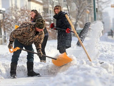 Patrick Boyle and Kara, left and Vesna Turk teamed up to clean their sidewalk in Kensington Wednesday December 20, 2017. An overnight winter storm hit Calgary leaving over 20 centimetres in parts of the city.