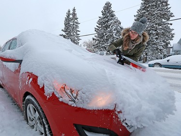 Alë Veffer clears snow from her car in Renfrew Wednesday December 20, 2017 after a winter storm hit Calgary leaving over 20 centimetres in parts of the city.