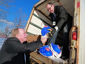 Peter Singleton hands up a turkey to Calgary Food Bank employee Joel Perry on Wednesday December 20, 2017. Singleton was among a group of business owner who bought 100 turkeys to donate to the food bank for the holidays. Gavin Young/Postmedia