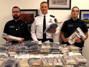 CBSA director Guy Rook (centre) and two CBSA agents display nearly 100 kg of cocaine seized at the Coutts border crossing on Dec. 2, 2017.