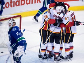 Vancouver Canucks goalie Jacob Markstrom  skates away as Calgary Flames defenceman Mark Giordano (No. 5) celebrates his goal with his teammates during the second period of NHL action in Vancouver, Sunday, Dec. 17, 2017.