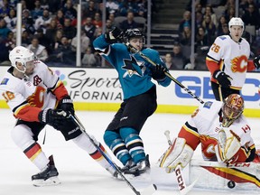 Calgary Flames goalie David Rittich stops a shot in front of San Jose Sharks' Chris Tierney, (centre) and Flames' Troy Brouwer (left) during the second period of an NHL hockey game Thursday, Dec. 28, 2017, in San Jose, Calif.