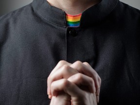 In this stock photo, a Catholic priest prays wearing a rainbow collar.