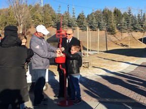 From left; Dave Dickinson and Lt Col. Larry Martin are with Collin Mathewson as he donates a bag of loonies.