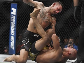 Max Holloway, top, punches Jose Aldo, of Brazil, during the third round of a UFC 218 featherweight mixed martial arts bout, early Sunday, Dec. 3, 2017, in Detroit. Holloway won the bout. (AP Photo/Jose Juarez)