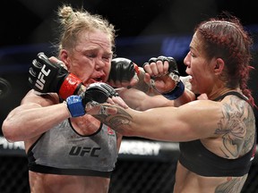 Cris 'Cyborg' Justino, right, hits Holly Holm during a featherweight championship bout at UFC 219, Saturday, Dec. 30, 2017, in Las Vegas.