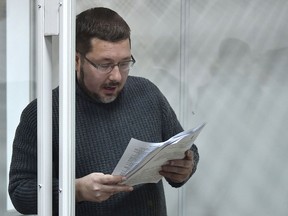 Stanislav Yezhov, a top government interpreter reads documents as he stands in a glass cage at the start of his hearing on suspicion of being a Russian spy at the courthouse in Kiev on Dec. 22, 2017. (GENYA SAVILOV/AFP/Getty Images)