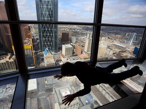 Charlie Whittier takes a view of the city from the glass floor inside the Calgary Tower in Calgary, Alta., on Sunday April 23, 2017. Tourism Calgary in a report to city council said last year saw just 7.2 million visitors to the city compared to 8 million in 2015.  Leah Hennel/Postmedia