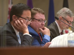 Councillors Sean Chu and Joe Magliocca look at the lengthy agenda for secondary-suite applications at City Hall in Calgary, Alta., on Monday, Sept. 12, 2016. Elizabeth Cameron/Postmedia