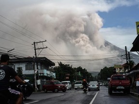 Motorists travel on a highway as Mount Mayon shot up a giant mushroom-shaped cloud as it continues to erupt near Camalig town, near Legazpi City in Albay province, south of Manila on January 22, 2018.