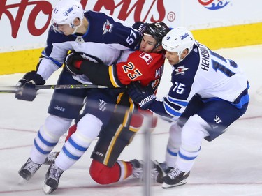 The Calgary Flames Sean Monahan took a holding penalty while sandwiched between the Winnipeg Jets' Tyler Myers and Matt Hendricks during NHL action at the Scotiabank Saddleome in Calgary on Saturday  January 20, 2018.