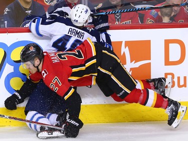 The Winnipeg Jets Joel Armia is checked by Dougie Hamilton during NHL action at the Scotiabank Saddleome in Calgary on Saturday January 20, 2018.