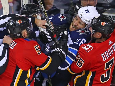 The Calgary Flames' Mark Giordano and Troy Brouwer get physical with the Winnipeg Jets' Blake Wheeler during NHL action at the Scotiabank Saddleome in Calgary on Saturday  January 20, 2018.